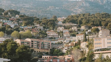 Residential area with modern buildings surrounded by lush greenery and a hilly landscape.