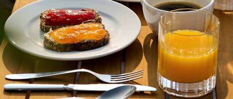A breakfast setting with toast, scrambled eggs, bacon, and orange juice on a wooden table.