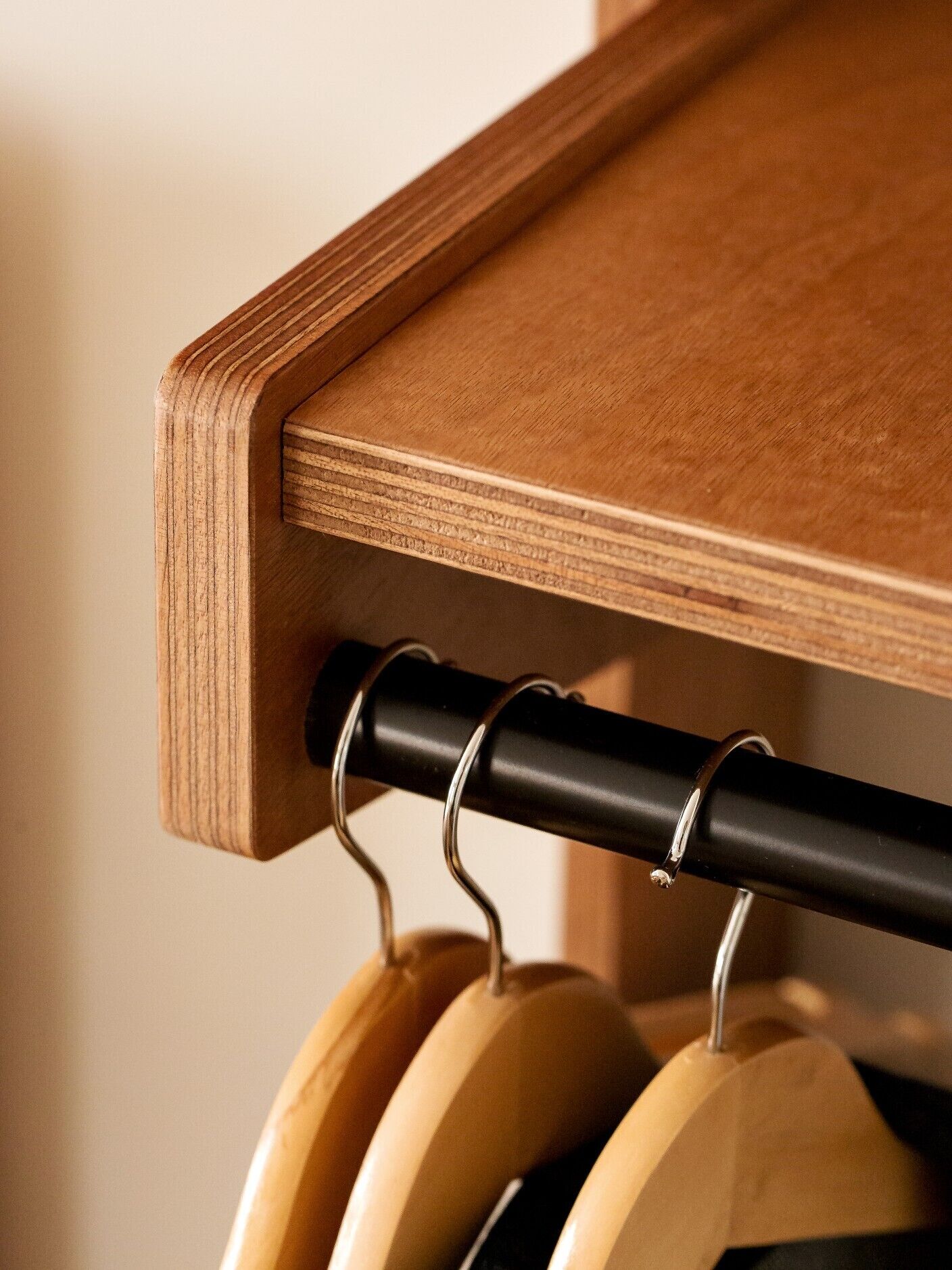 Een houten plank met een zwarte metalen stang en houten kledinghangers.