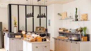 Una cocina moderna con una isla central, iluminación colgante y una variedad de electrodomésticos y utensilios de cocina.
