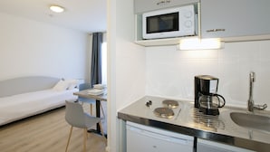 Una kitchenette compacta con microondas, cafetera y pileta.