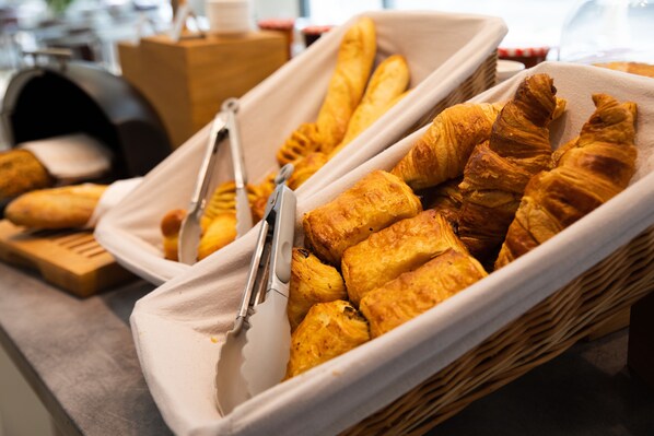Una cesta de cruasanes y una baguette sobre una mesa.