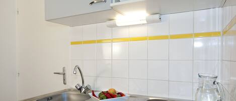 A modern kitchen with a stainless steel sink, a microwave, and a glass pitcher on the counter.