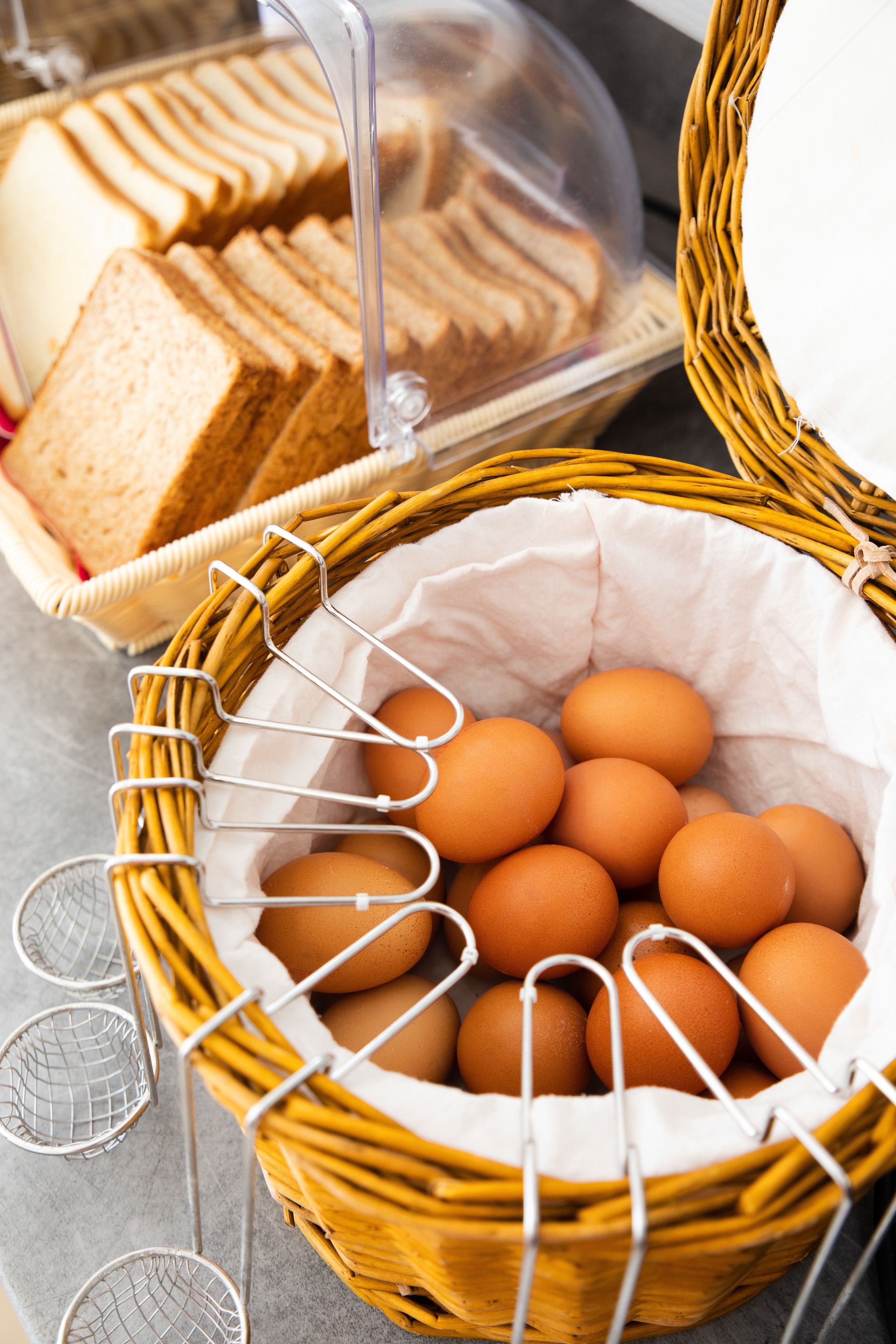 A wicker basket filled with eggs and a wicker basket containing bread.