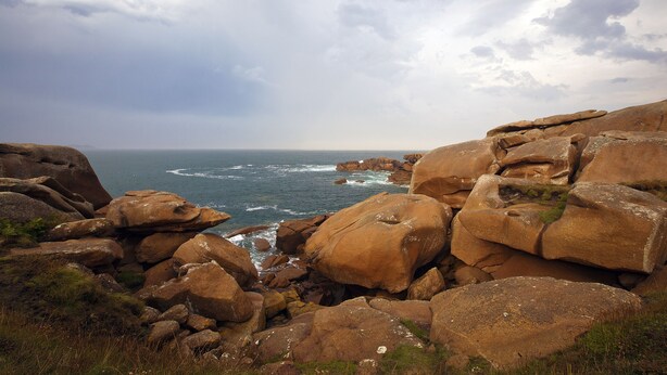 Una costa rocosa con grandes rocas y el océano al fondo.