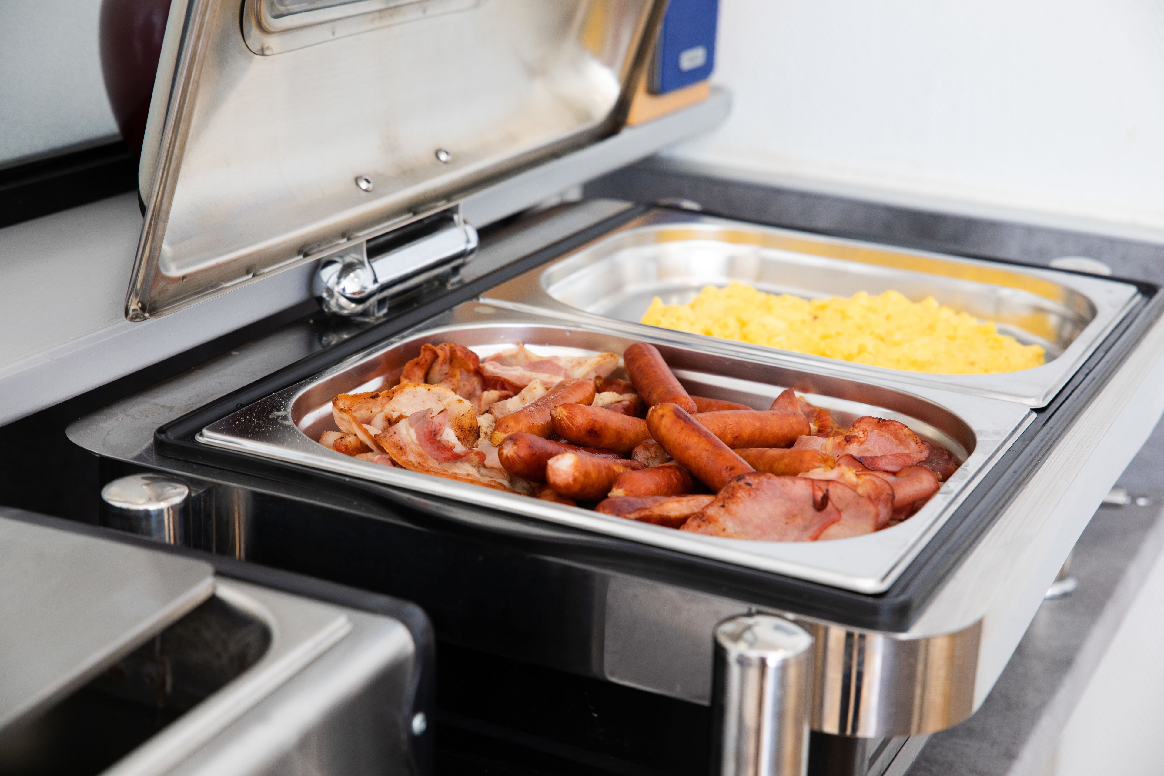 Un buffet proposant différents plats, notamment des saucisses et des œufs brouillés.