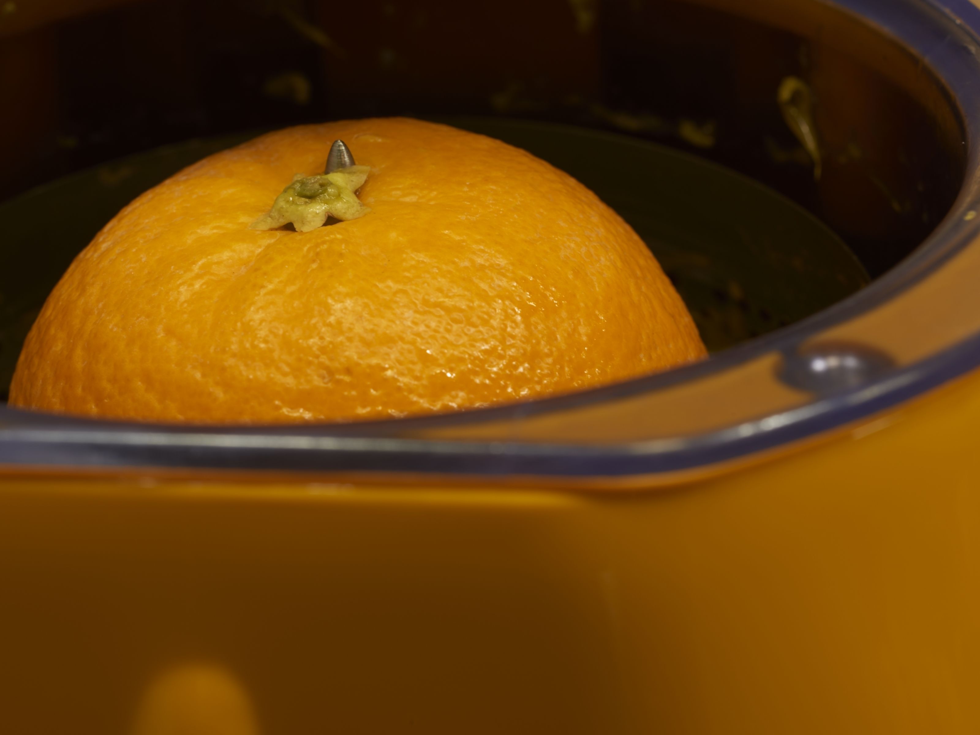 An orange in a yellow container.