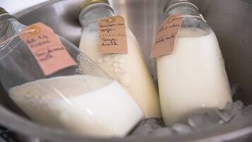 Tres botellas de leche con etiquetas en un recipiente metálico.