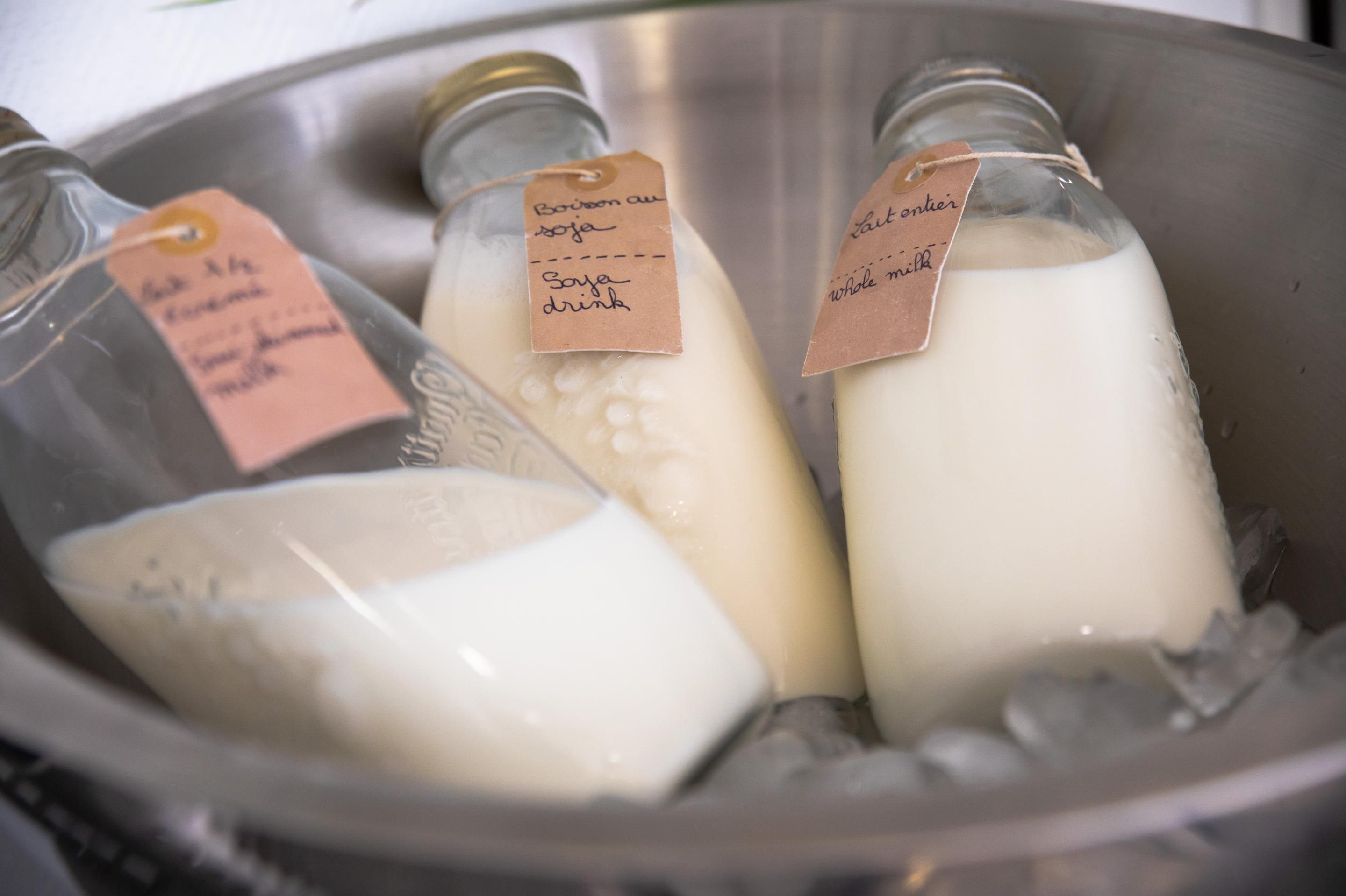 Trois bouteilles en verre, étiquetées, contenues dans un récipient en métal.
