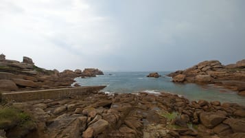 Un paisaje costero rocoso con grandes rocas y un mar tranquilo.
