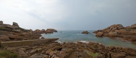 Eine felsige Küstenlandschaft mit großen Felsen und ruhiger See.
