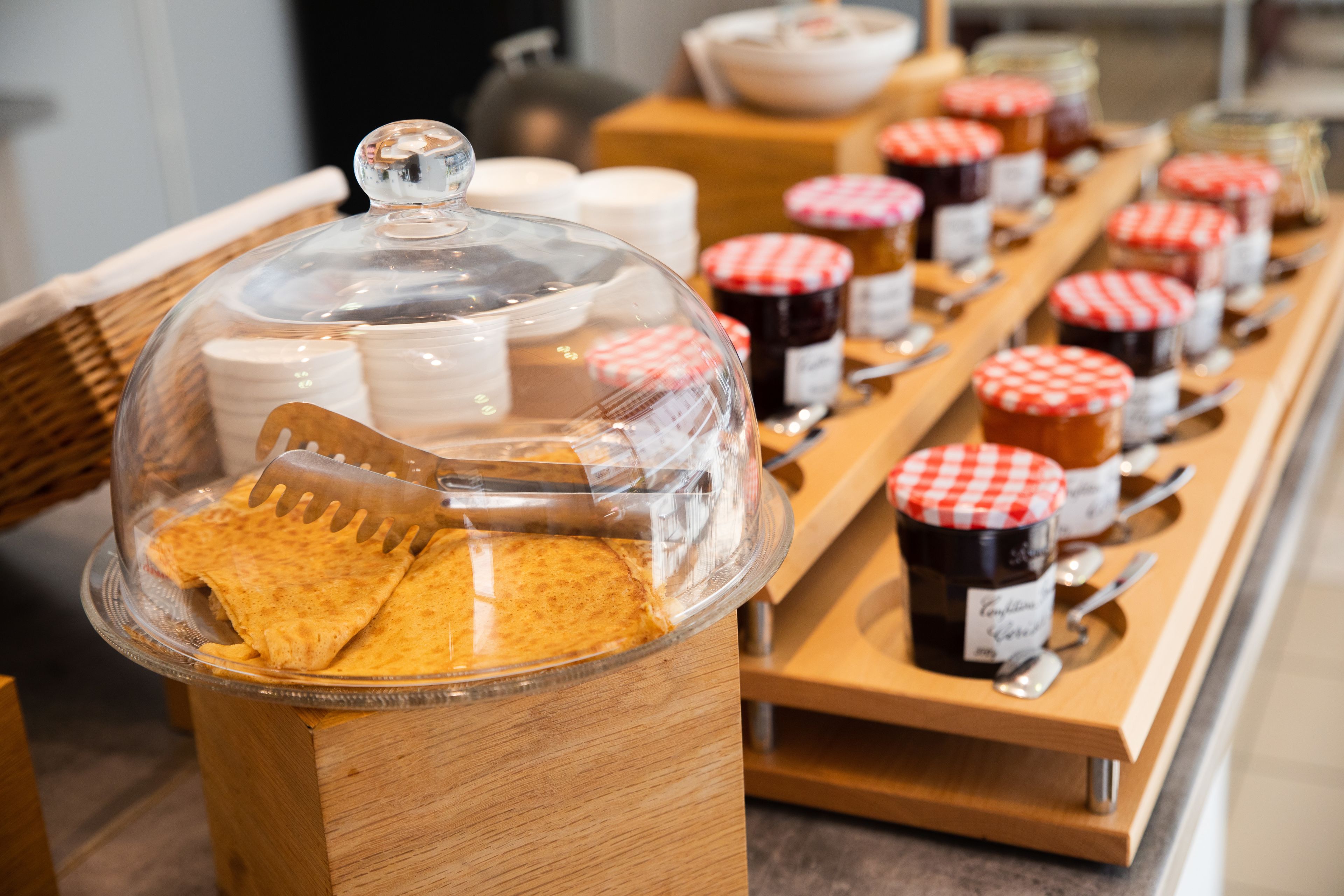 Un buffet proposant une variété de plats, notamment un plat couvert contenant des tortillas et une sélection de confitures et de pâtes à tartiner.
