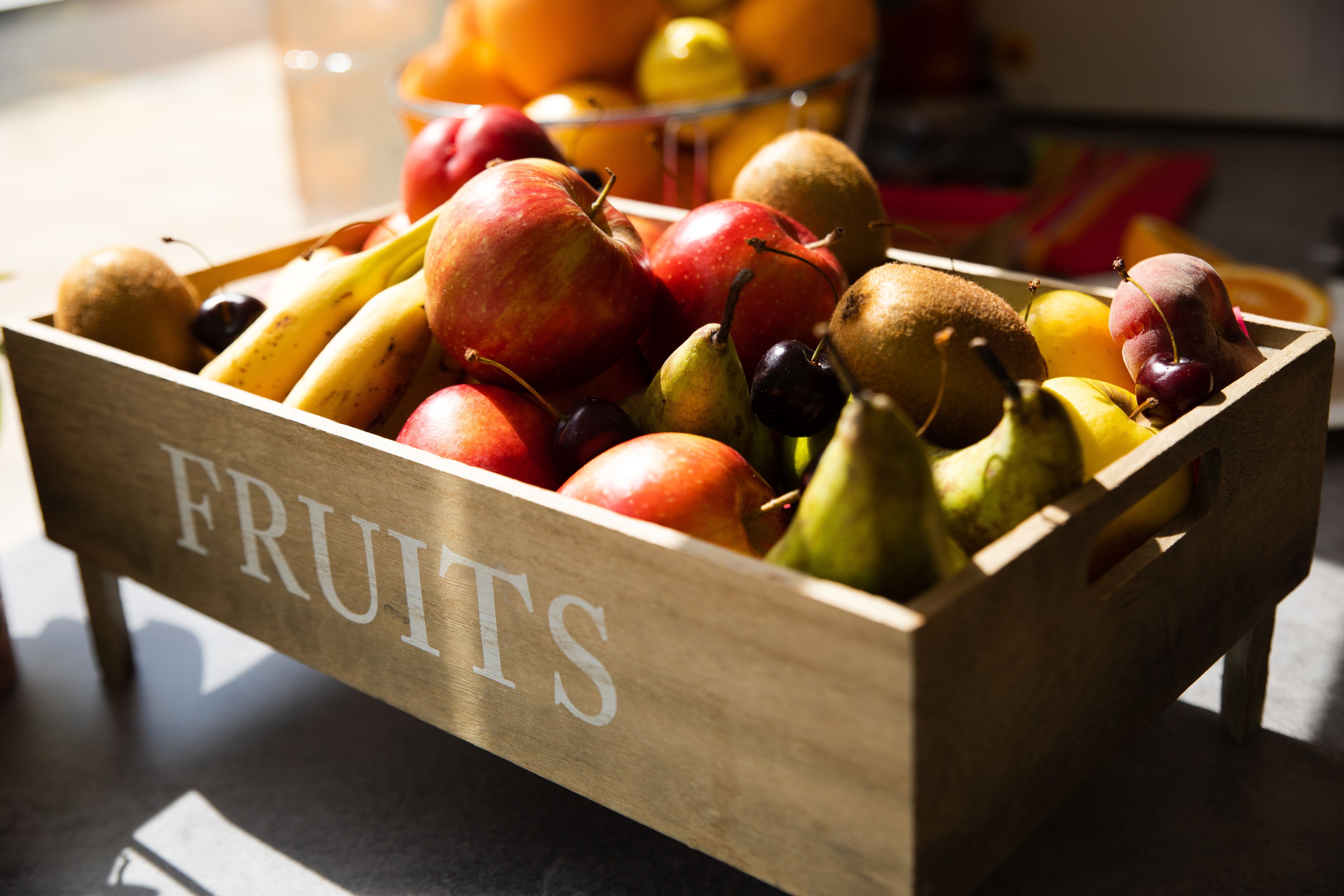 A wooden crate labeled "FRUITS" filled with various fruits like apples, pears, and bananas.