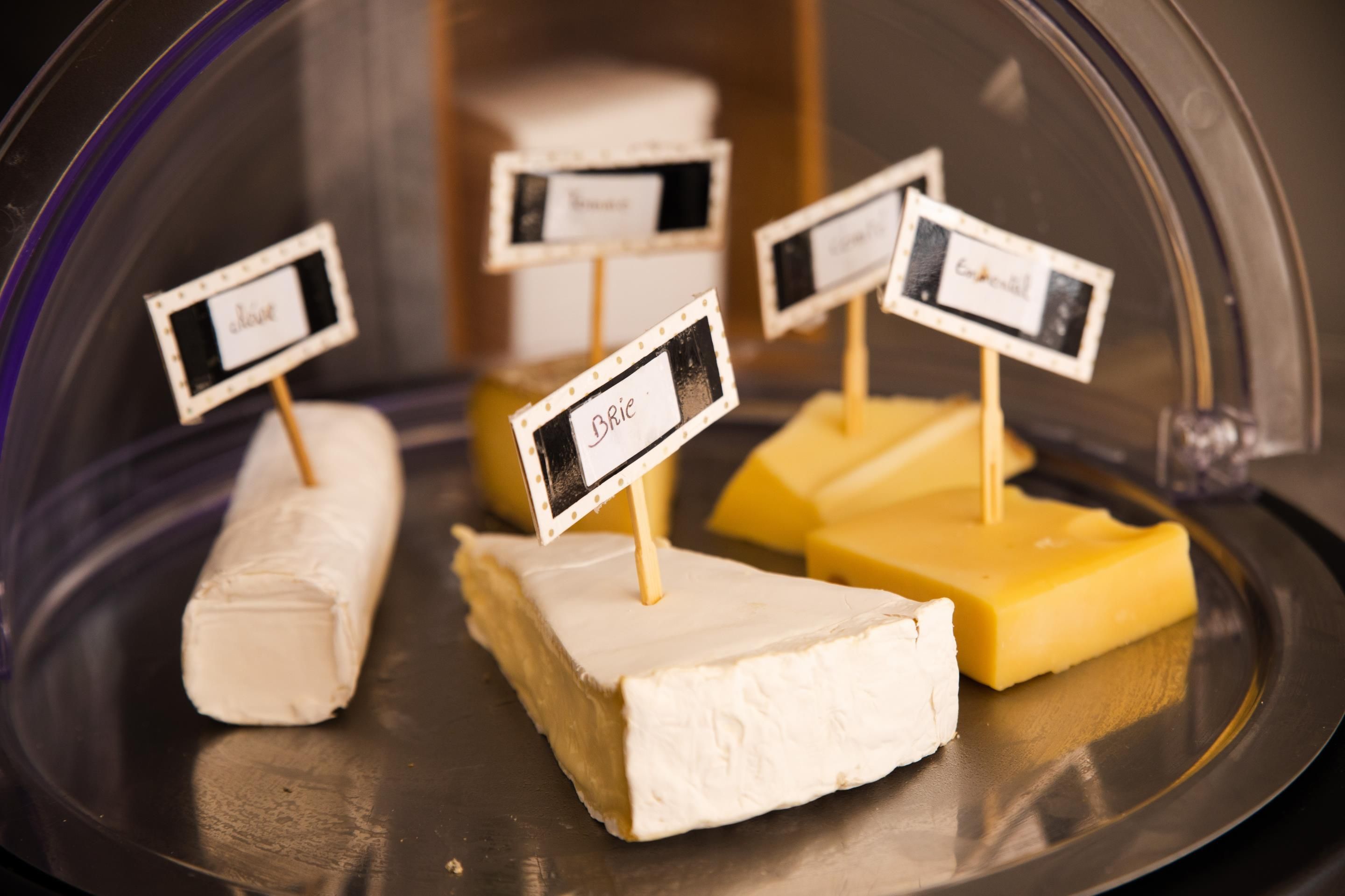A cheese display with labels under a glass dome.