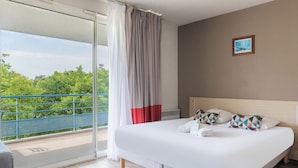 A hotel room with a large bed, a view of greenery through the balcony, and a framed picture on the wall. - Appart'City Classic La Rochelle Centre (La Rochelle)