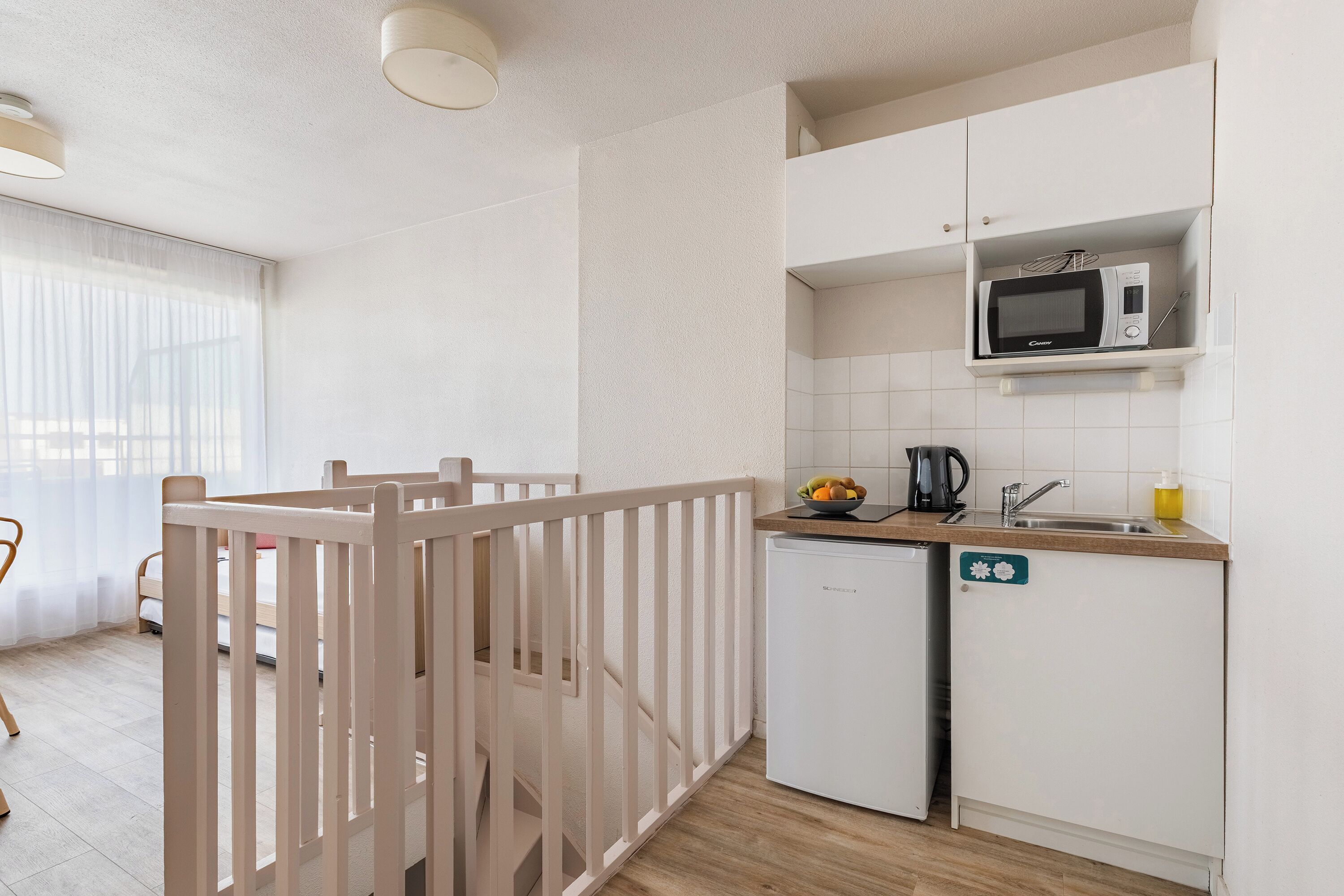 Una cocina compacta equipada con microondas, fregadero y refrigerador pequeño.
