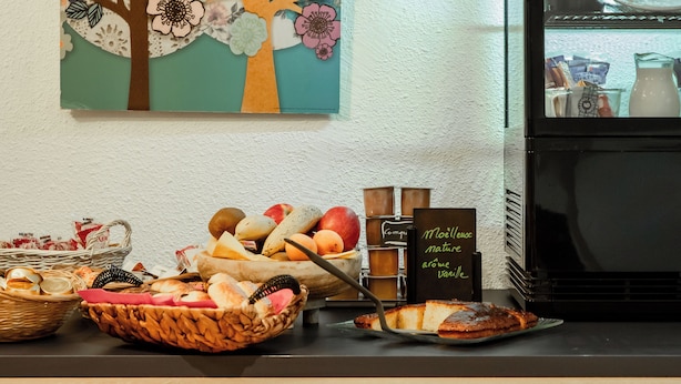Un bufé de desayuno con diversas frutas, panes y bollería.