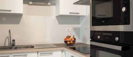 A modern kitchen with white cabinets, a stainless steel sink, a black microwave, and an oven.