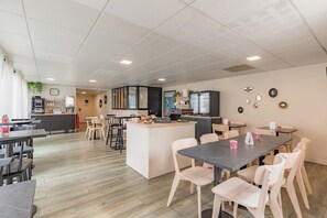 A modern dining area with a central island, multiple tables, and chairs. - Appart'City Classic Nantes Quais de Loire (Nantes)