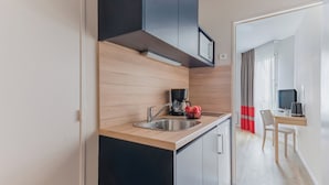 Una cocina moderna con encimera de madera, pileta de acero inoxidable y armarios negros. Hay una cafetera y un frutero pequeño sobre la encimera.