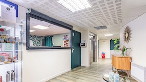 Un vestíbulo moderno de hotel con una recepción, un aparador de madera y una vitrina de cristal con detalles.