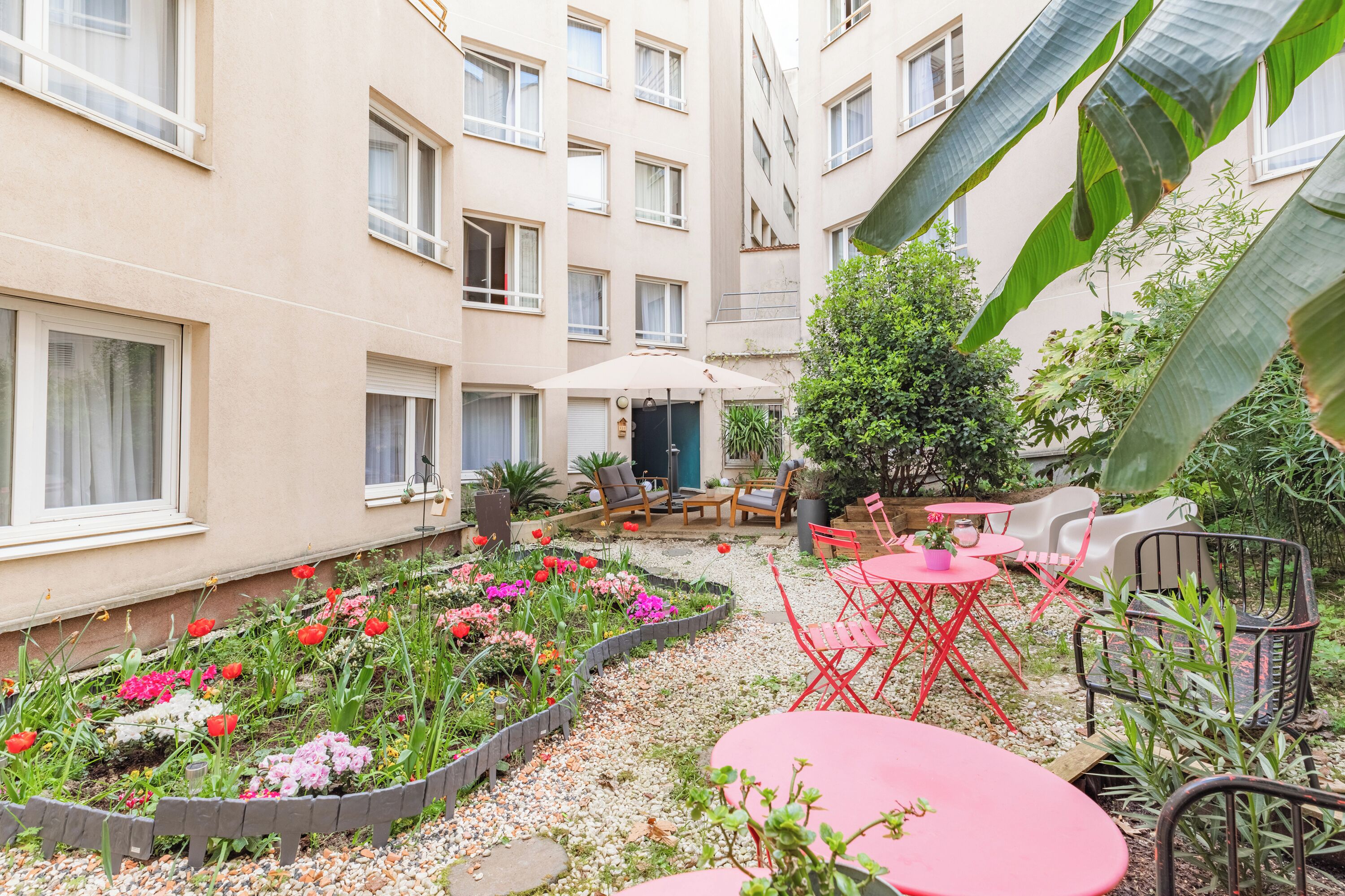 A courtyard with a garden, outdoor seating, and a building facade.