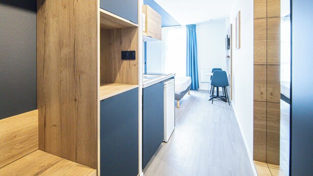 A modern hotel room with a wooden bench, a desk, and a chair. - City Residence Nancy (Nancy)