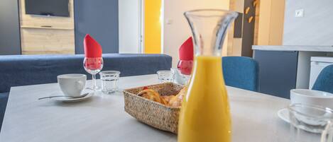 A dining table with breakfast items, a bottle of juice, and a TV in the background.