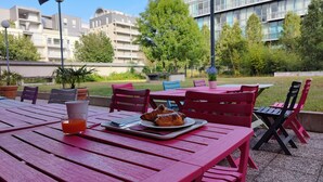 An outdoor dining area with tables and chairs, a plate with croissants, and a glass of orange juice. - City Residence Nancy (Nancy)