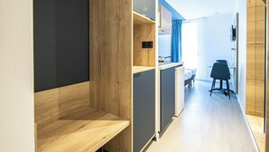 A modern hotel room with a wooden wardrobe, a desk, and a chair. - City Residence Nancy (Nancy)