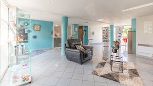 A spacious lobby with a leather sofa, a glass display case, and a potted plant. - Appart'City Classic Rennes Ouest (Rennes)