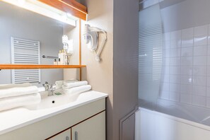 A bathroom with a white sink, a mirror, a hairdryer, and a towel rack.