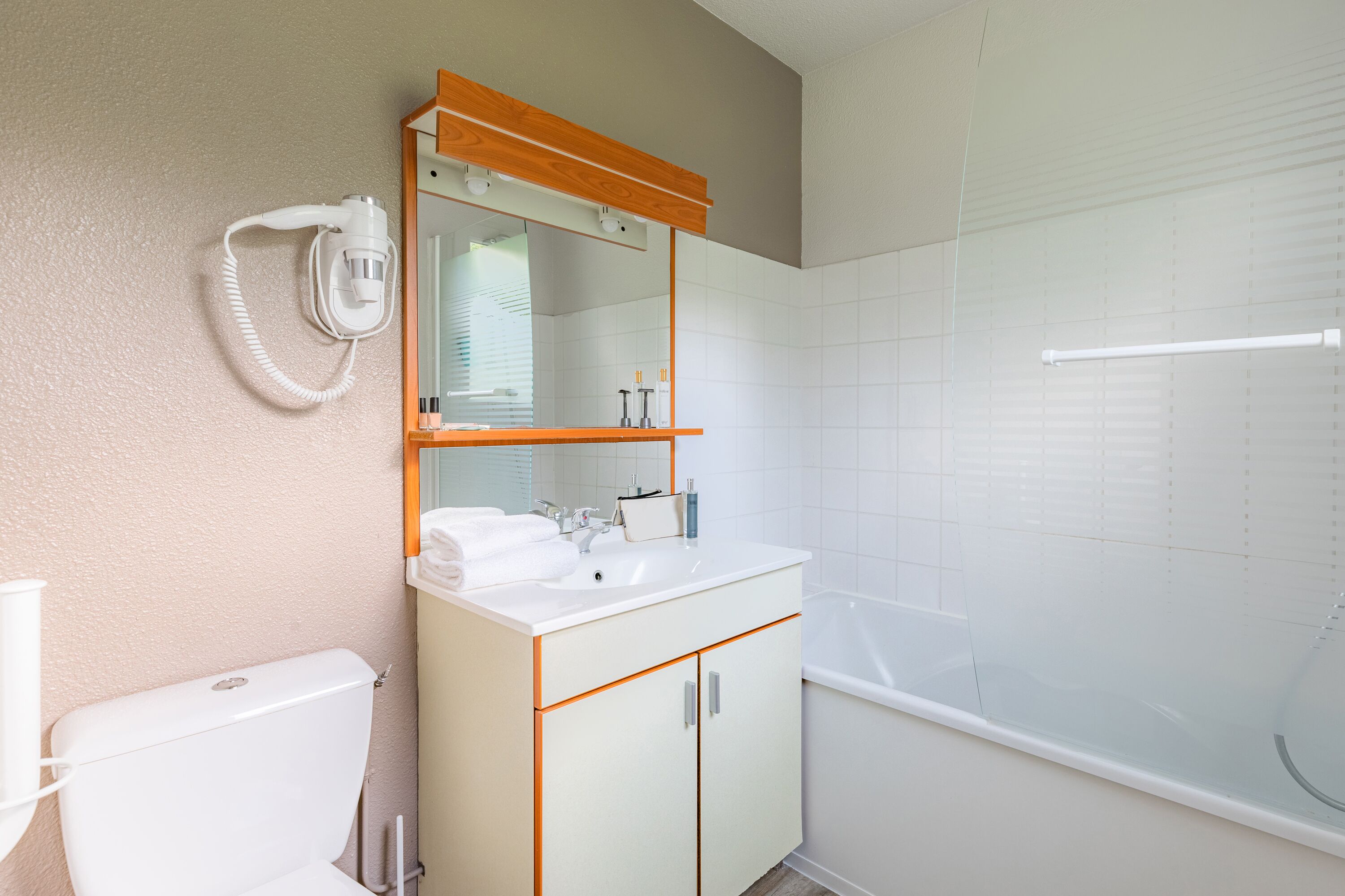 Een badkamer met een wit wastafel, spiegel en toilet.