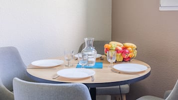 A round dining table with four plates, a pitcher, and a fruit basket.