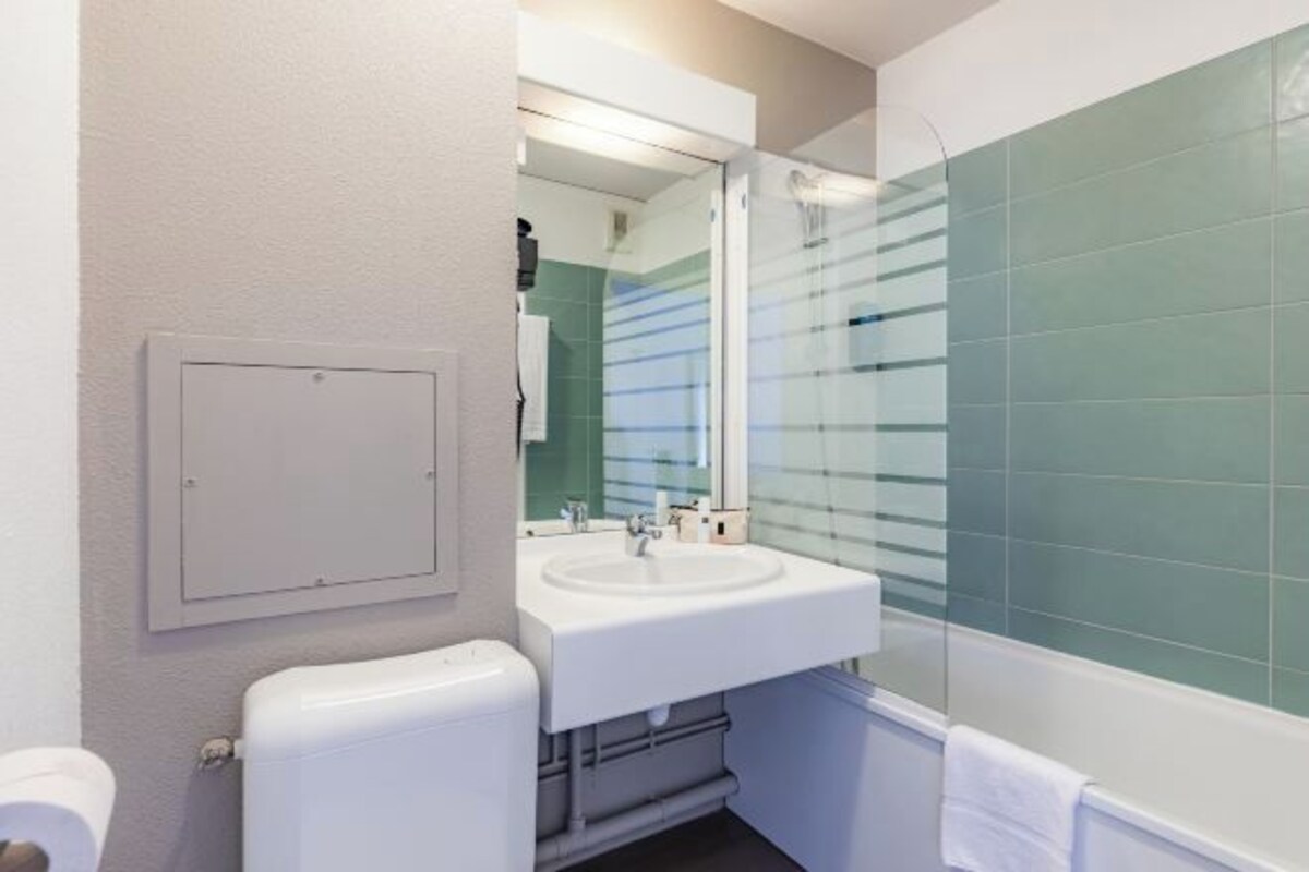 Un baño con un lavabo blanco, un espejo y una cabina de ducha de vidrio.