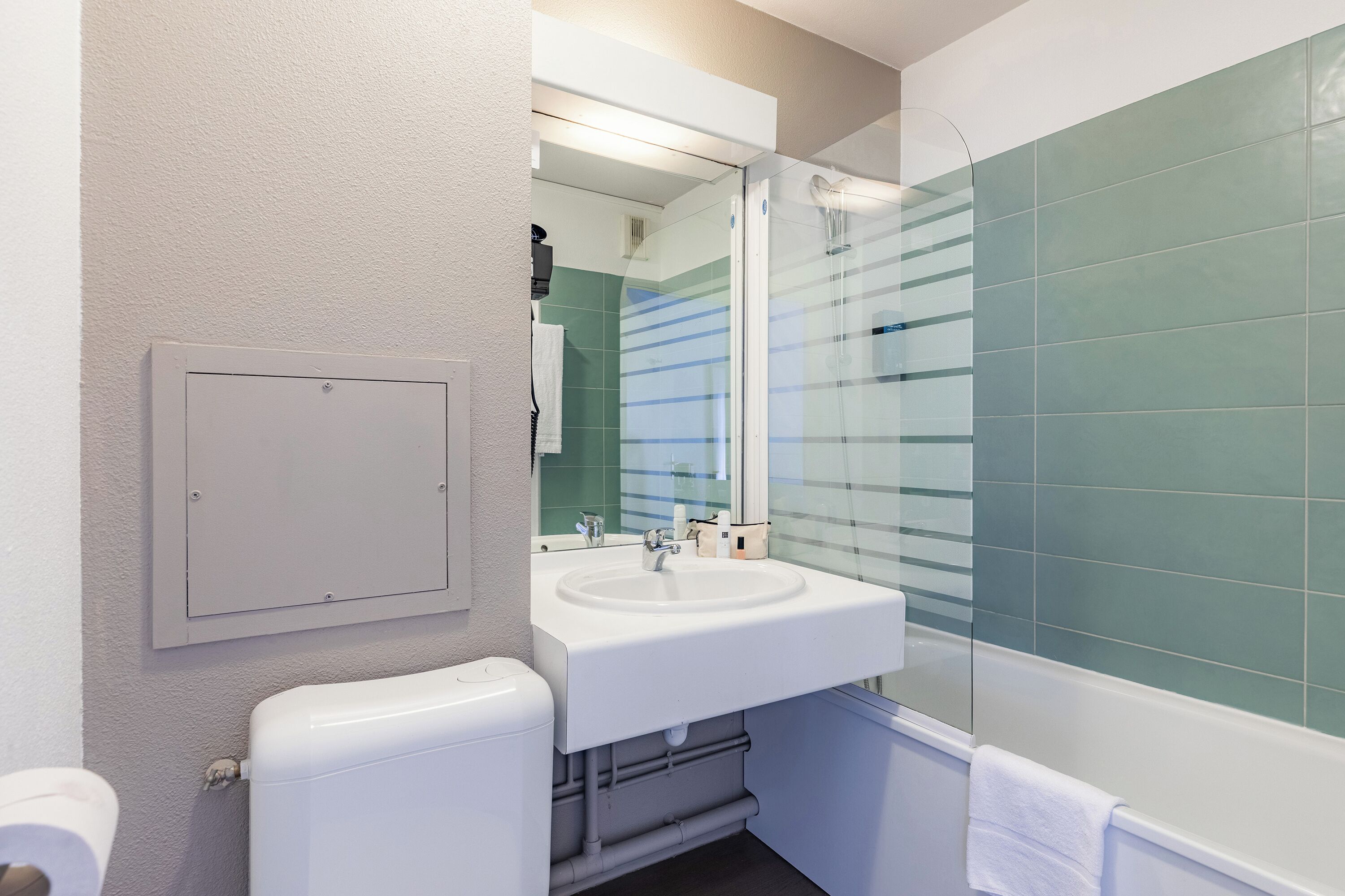 Een moderne badkamer met een witte wastafel, een glazen douchecabine en een toilet.