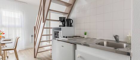 A modern kitchen with a built-in stove, a sink, and a wooden staircase.