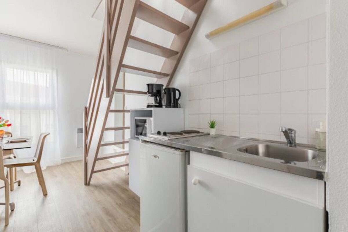 Una cocina moderna con estufa integrada, un lavamanos y una escalera de madera.