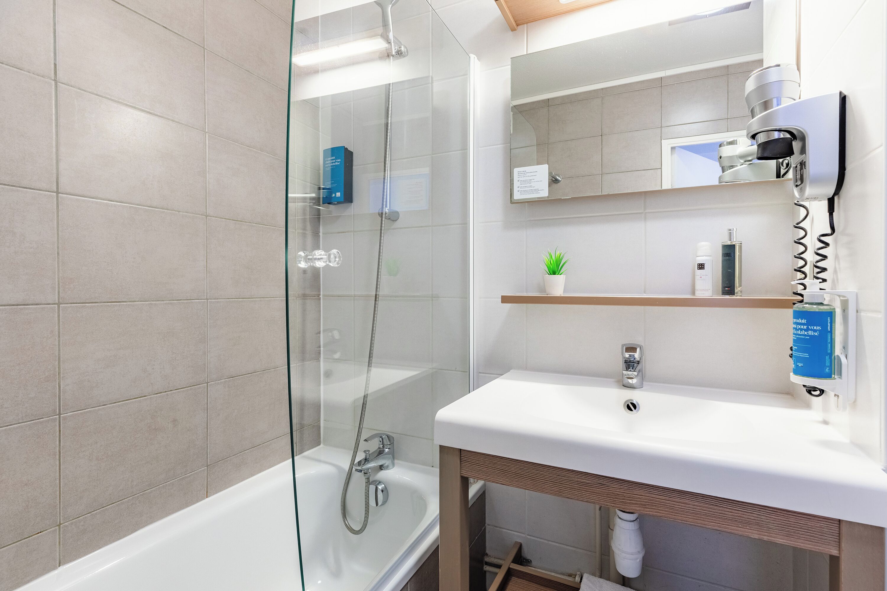 Un baño moderno con ducha de vidrio, lavamanos blanco y espejo sobre el lavamanos.