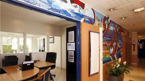 A conference room with a large mural, a wooden desk, and a potted plant. - Appart'city Classic Lyon Part Dieu Garibaldi (Lyon)