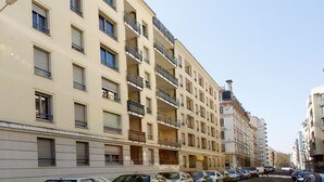 A multi-story residential building with balconies, parked cars, and a clear sky. - Appart'city Classic Lyon Part Dieu Garibaldi (Lyon)