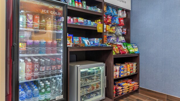 A vending machine area with various snacks and drinks, including ice cold beverages and a refrigerator with bottled water. - City Express By Marriott Elkridge (Elkridge)