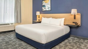 A hotel room with a bed, two bedside lamps, a wall-mounted artwork, and a window with curtains. - City Express By Marriott Elkridge (Elkridge)