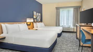 A hotel room with two beds, a desk, a TV, and a window with curtains.