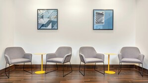 A waiting area with four grey armchairs, two yellow tables, and two framed abstract artworks on the wall. - City Express By Marriott Elkridge (Elkridge)