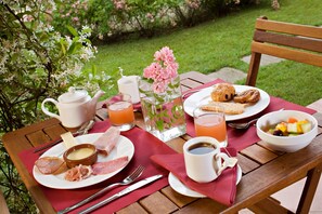 A table set with breakfast items including eggs, ham, cheese, toast, fruit, and beverages.