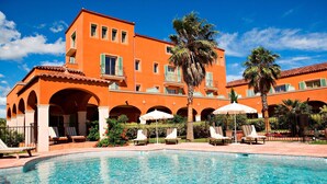 Un hotel con piscina, tumbonas y palmeras.