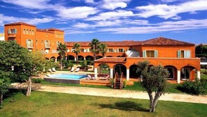 Un gran complejo turístico con varias edificaciones, piscina y palmeras.