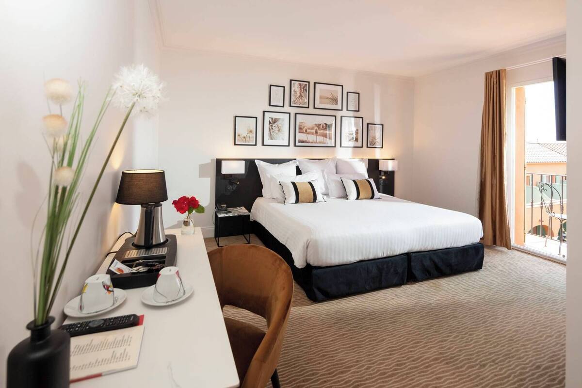 Une chambre d’hôtel avec un grand lit, un bureau avec une lampe, une chaise et une vue sur l’extérieur.