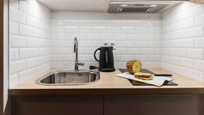 Une cuisine avec un évier en acier inoxydable, une bouilloire noire et une miche de pain posée sur le comptoir.